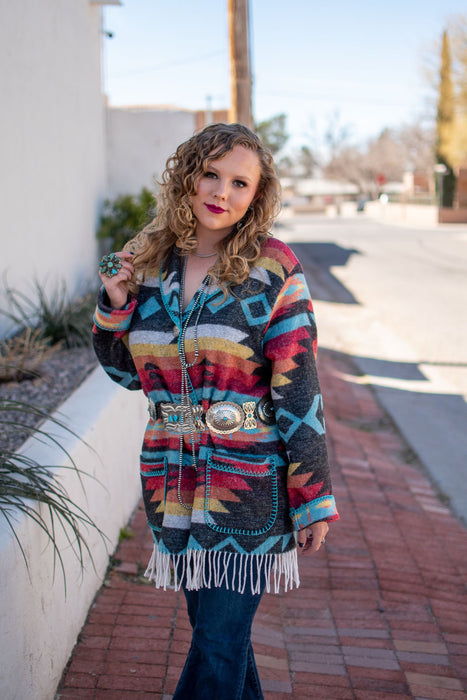 This car coat is truly one of a kind. With its bold aztec print and fringe detailing, it's sure to be a piece that you'll reach for time and time again. It's also a perfect mid-weight fabric for transitioning into spring.   As with all of our pieces by Rhonda Stark Designs, this piece is handmade in the USA and the fabric comes directly from Italy. 