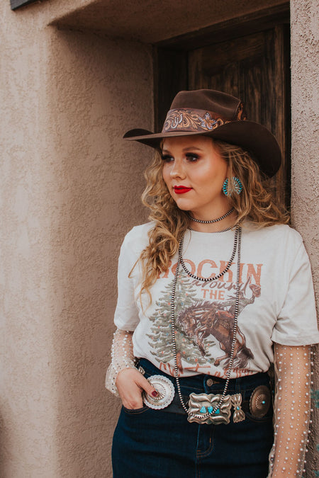 I know what I'm asking Santa for this year! This comfy graphic tee features a buckin' bronco and a festive Christmas tree. It's giving the perfect cowboy Christmas vibes.  Our favorite style pick? Pairing it with our rhinestone cowgirl mesh top to elevate your whole look!