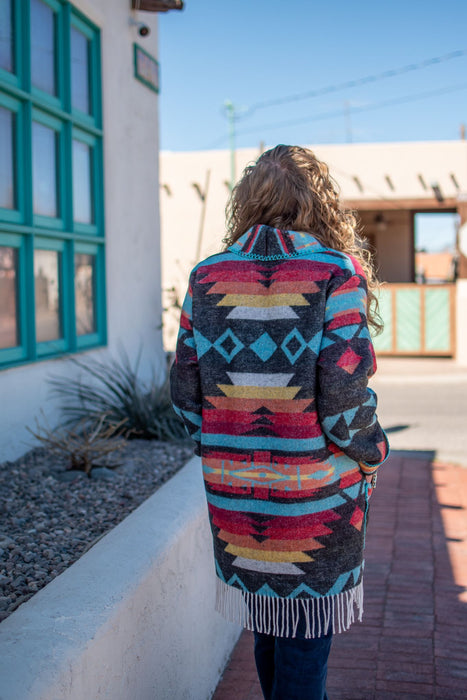 This car coat is truly one of a kind. With its bold aztec print and fringe detailing, it's sure to be a piece that you'll reach for time and time again. It's also a perfect mid-weight fabric for transitioning into spring.   As with all of our pieces by Rhonda Stark Designs, this piece is handmade in the USA and the fabric comes directly from Italy. 