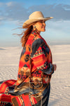 This long blanket-coat style duster is a truly elevated fashion piece. It has a bold aztec pattern of orange, red, and deep blue and hits about ankle length. The buttons are classic style conchos, and its so comfortable you won't want to take it off.   As with all of our pieces by Rhonda Stark Designs, this piece is handmade in the USA and the fabric comes directly from Italy. 