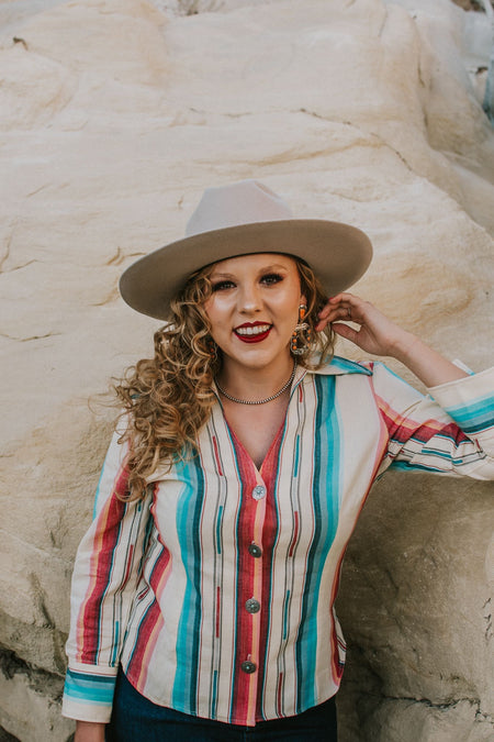 Silverado Apparel never misses, and this stunning blouse is no exception! The Sedona features a bold serape pattern and one of the most stunning silhouettes we offer: dramatic 3/4 sleeves, a fitted waistline and a stunning v- neck. This top is sure to become a staple in your wardrobe.   Handmade in Texas by Silverado Apparel.  Colorado crystal.