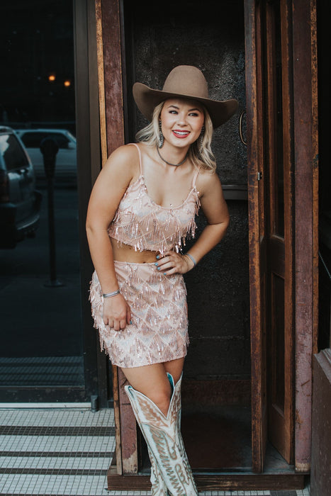 Vegas Nights + Rodeo Lights: The NFR Collection. Two piece chandelier fringe skirt and top paired with cowboy hat. rose gold sequins. 